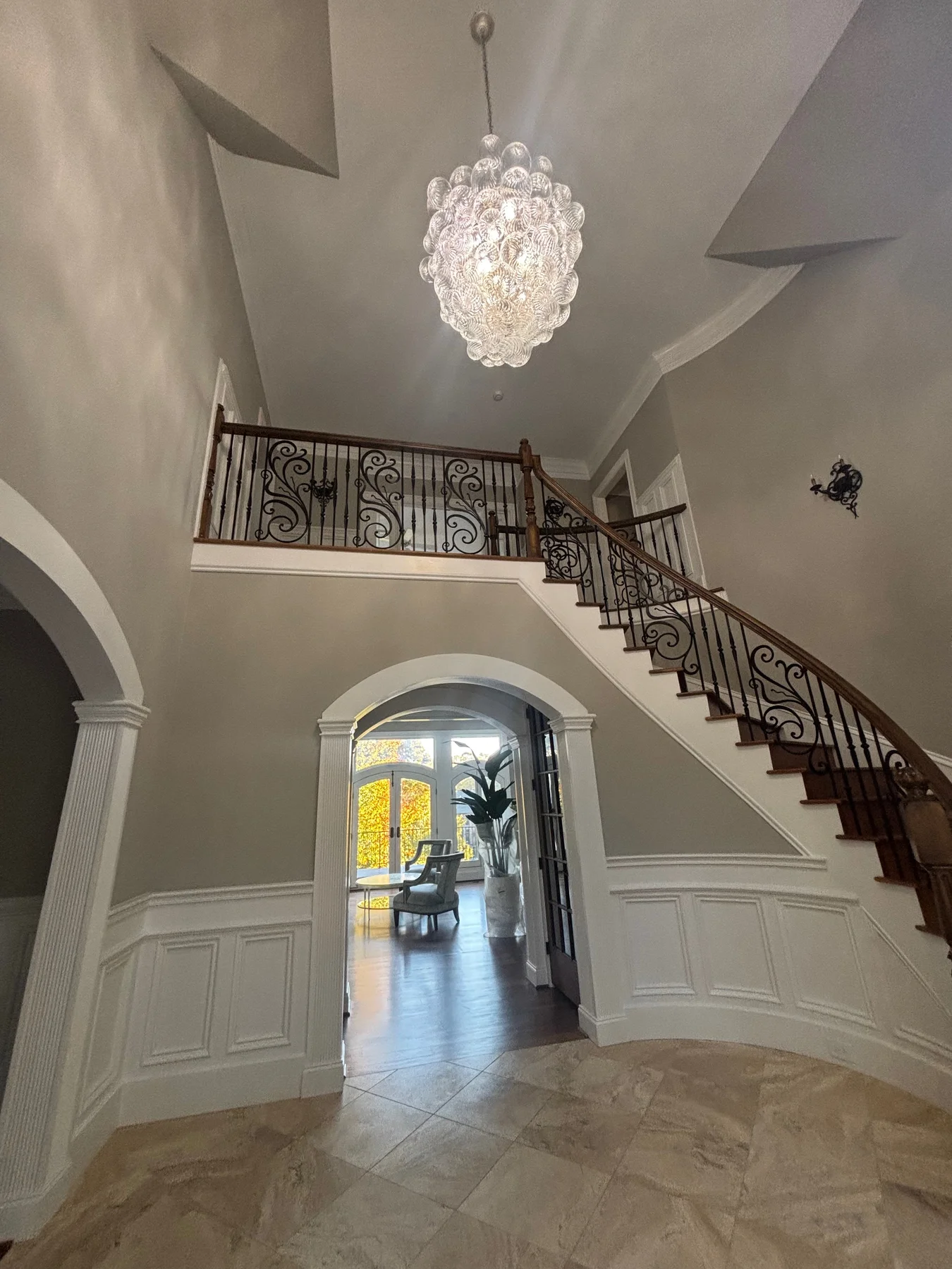 Completed residential foyer lighting with a chandelier and curved staircase