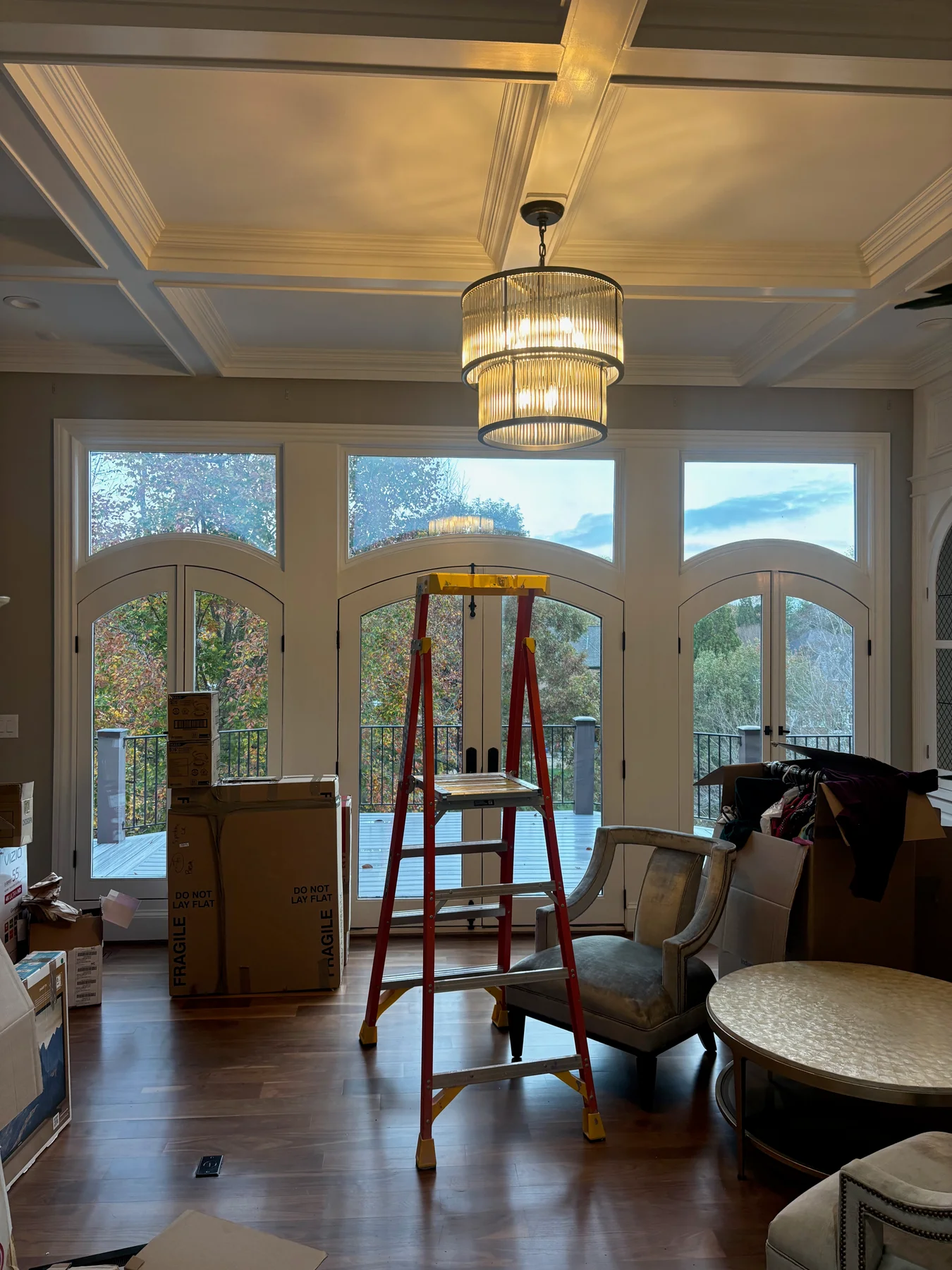 Gold-toned tiered chandelier during installation